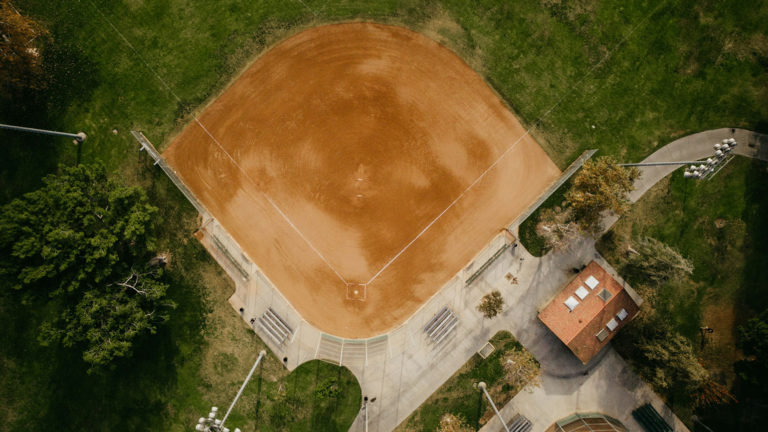 A baseball field in the middle of a field near a house mirrors the classic baseball movie "Field of Dreams."